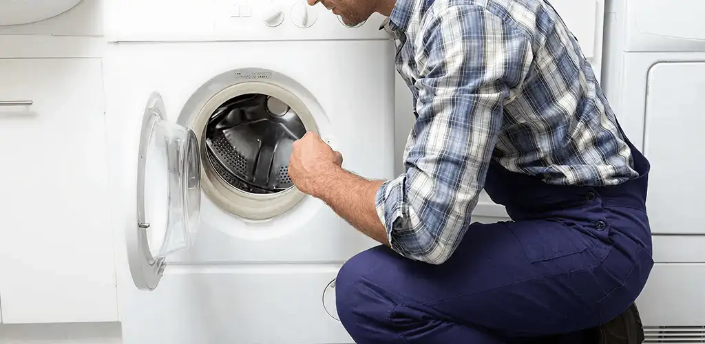 Handyman inspecting a dryer drum and internal parts for repair in New Haven, CT