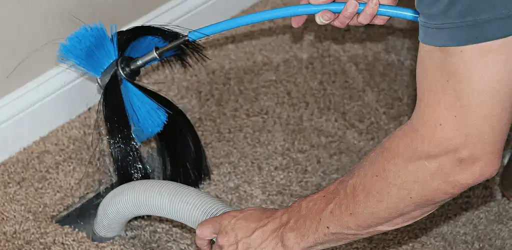 Dryer vent cleaning technician brushing lint from a vent line in New Haven, CT