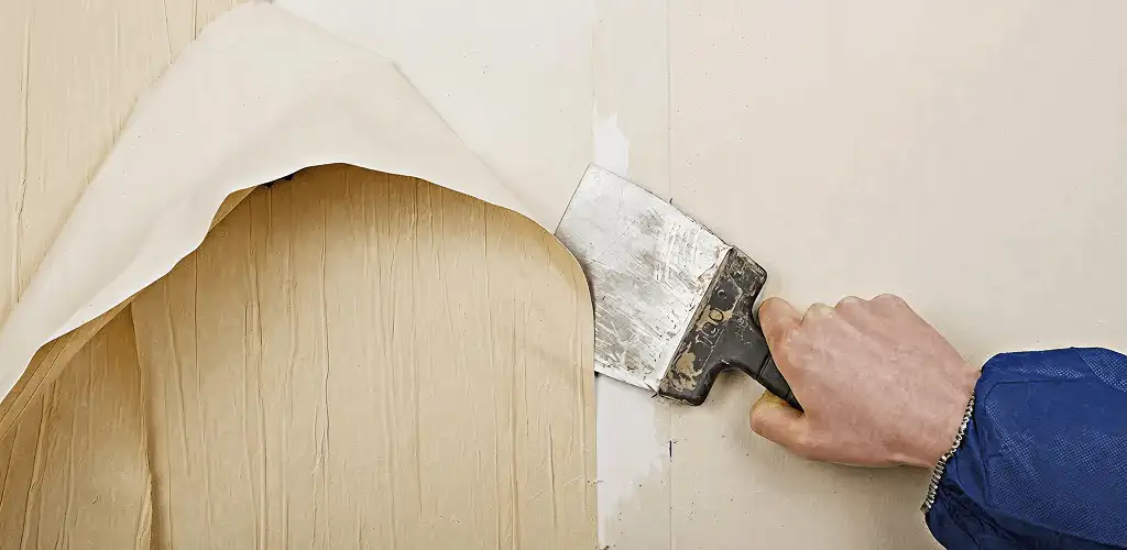 Handyman removing wallpaper with a scraper for wall preparation in New Haven, CT