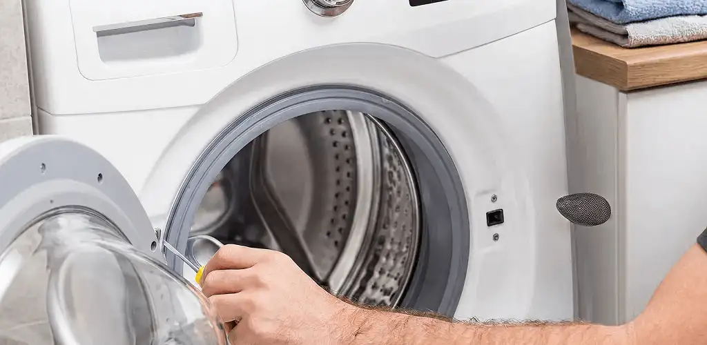 Handyman repairing a front-load washing machine and inspecting the drum in New Haven, CT