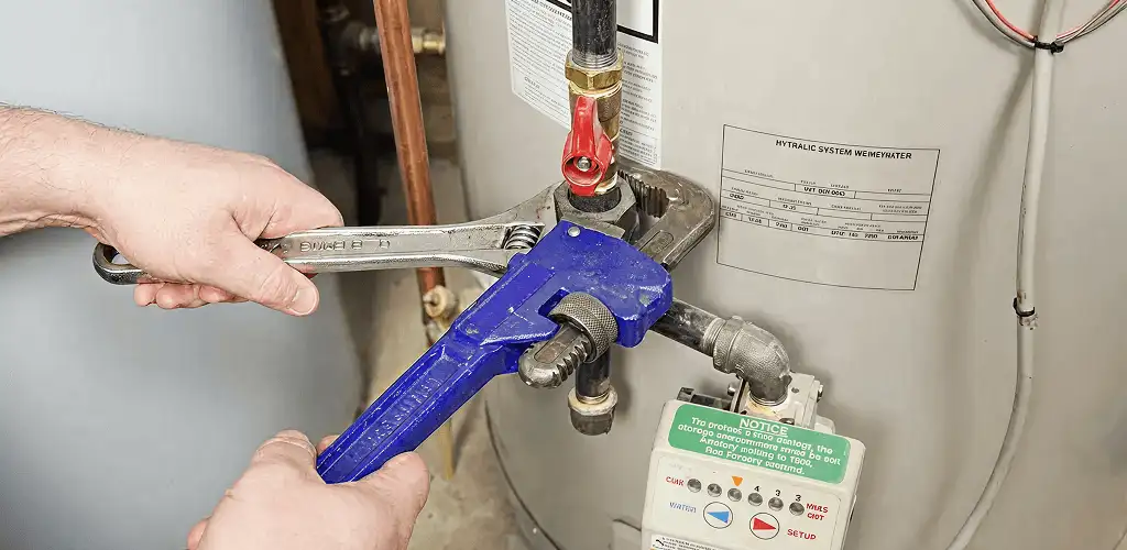 Water heater repair technician tightening the shutoff valve and supply line in New Haven, CT